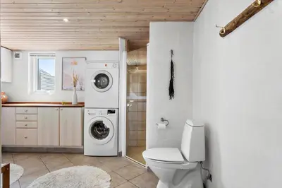 a bathroom with a toilet and a washer and dryer at BL509-Blokhus-Jens-Baerentsvej-7 in Blokhus