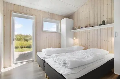 a bedroom with a large bed and a window at BL1748-Blokhus-Grossvej-5 in Blokhus