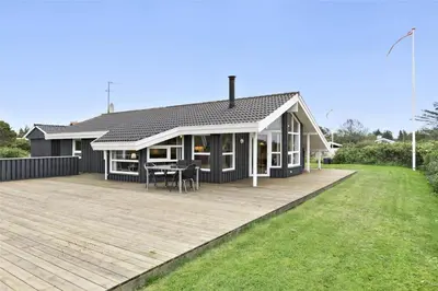a house with a deck with a table on it at BL314-Blokhus-Bakkevaenget-5 in Blokhus
