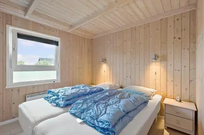 a bedroom with a bed with blue sheets and a window at BL314-Blokhus-Bakkevaenget-5 in Blokhus