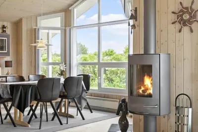 a living room with a fireplace and a table with chairs at BL314-Blokhus-Bakkevaenget-5 in Blokhus