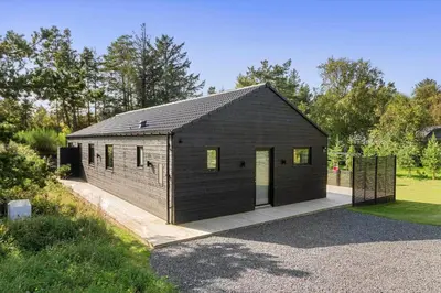 a black building with a door on a driveway at BL1485-Blokhus-Jaegervaenget-2-A in Blokhus