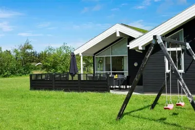 a house with a porch and an umbrella in the grass at BL1633-Saltum-Nordvestvej-18 in Saltum