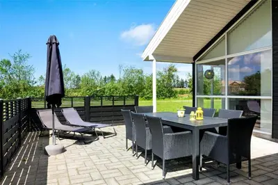 a patio with a black table and chairs and an umbrella at BL1633-Saltum-Nordvestvej-18 in Saltum