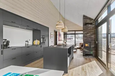 a kitchen with black cabinets and a fireplace at BL1433-Blokhus-Mollevej-11 in Blokhus