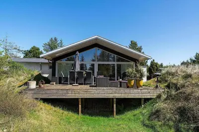 a house with a wooden deck in the grass at BL1420-Blokhus-Ronliensvej-21 in Blokhus