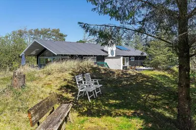 a table and chairs sitting on a hill in front of a house at BL1420-Blokhus-Ronliensvej-21 in Blokhus