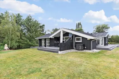a black house on a yard with a grass field at BL1492-Blokhus-Plantagevej-19-B in Blokhus