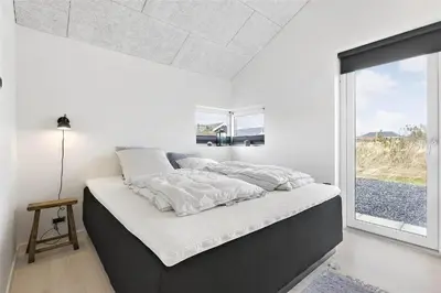 a bed in a room with a large window at BL1667-Blokhus-Klitvejen-24 in Blokhus