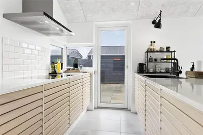 a kitchen with white walls and wooden cabinets at BL1667-Blokhus-Klitvejen-24 in Blokhus