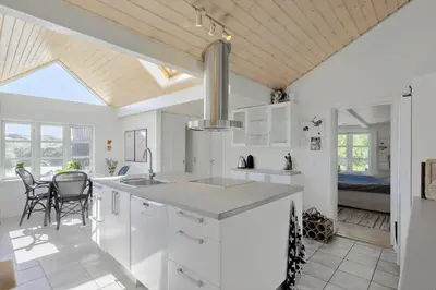 a kitchen with white cabinets and a table and chairs at BL1273-Blokhus-Vester-Klitvej-15 in Blokhus