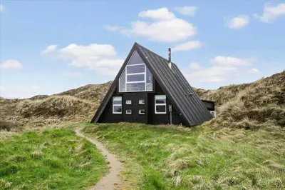 a black house on top of a grassy hill at BL1738-Pandrup-Narhvalen-11 in Pandrup