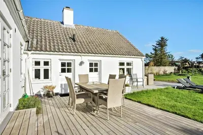 a wooden deck with a table and chairs at BL327-Blokhus-Sonder-I-By-23 in Blokhus