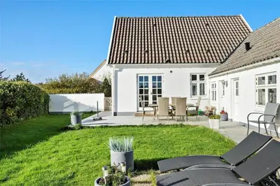 a white house with chairs and a yard at BL327-Blokhus-Sonder-I-By-23 in Blokhus