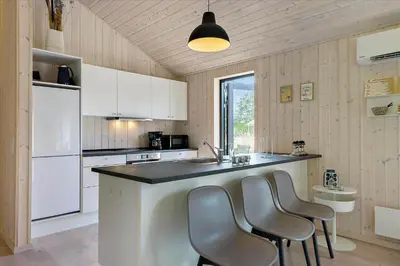 a kitchen with white cabinets and a counter with chairs at BL1513-Blokhus-Gyldenrisvej-18 in Blokhus