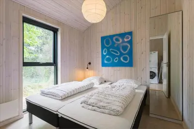 two beds in a room with a large window at BL1513-Blokhus-Gyldenrisvej-18 in Blokhus
