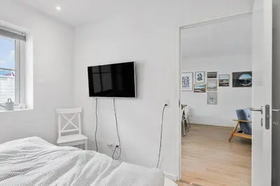 a white bedroom with a tv on a white wall at BL1708-Blokhus-Klitgaardsvej-3-D in Blokhus