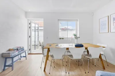 a dining room with a wooden table and white chairs at BL1708-Blokhus-Klitgaardsvej-3-D in Blokhus