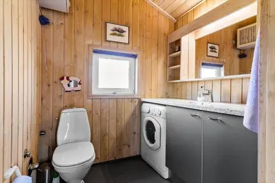 a bathroom with a toilet and a washing machine at BL1378-Blokhus-Klitvejen-65 in Blokhus