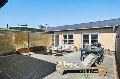 a patio with a table and chairs and an umbrella at BL1209-Blokhus-Bellevueparken-14 in Blokhus