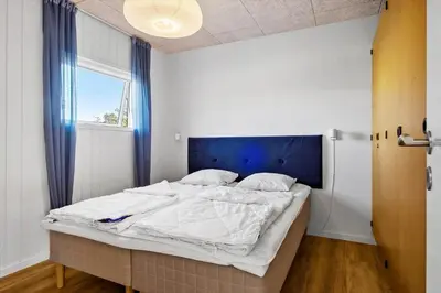 a bedroom with a bed with a blue headboard and a window at BL1209-Blokhus-Bellevueparken-14 in Blokhus