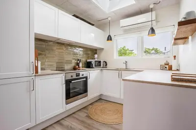 a white kitchen with white cabinets and a wooden floor at BL1209-Blokhus-Bellevueparken-14 in Blokhus