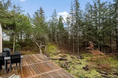 a wooden deck with a table in the woods at BL1327-Blokhus-Braendevinsstien-5 in Blokhus