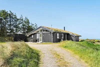 a black building with a grass roof on a dirt road at BL1428-Saltum-Karen-Mariesvej-31-D in Saltum