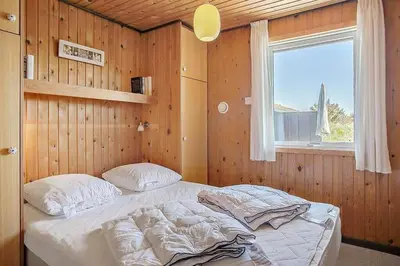a bed in a wooden room with a window at BL1497-Pandrup-Hunetorp-Klitvej-271 in Pandrup