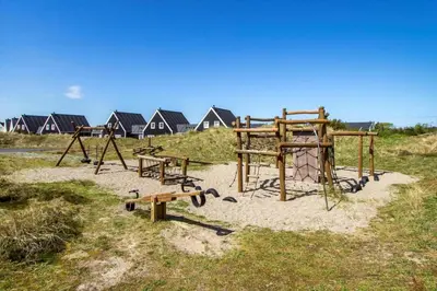 a park with benches and a playground with houses in the background at BL1443-Blokhus-Ferren-Syd-46 in Blokhus