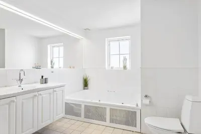 a white bathroom with a tub and a toilet at BL1443-Blokhus-Ferren-Syd-46 in Blokhus