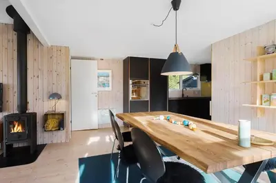 a kitchen and dining room with a wooden table and a fireplace at BL1589-Saltum-Bondagervej-52 in Saltum