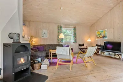 a living room with a fireplace and a living room with a couch at BL1786-Saltum-Ornebjergvej-22 in Saltum