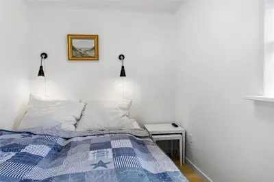 a bed with a blue and white comforter in a bedroom at BL395-Blokhus-Maren-Hjortelsvej-4 in Blokhus