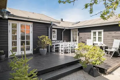 a house with a wooden deck with a table and chairs at BL395-Blokhus-Maren-Hjortelsvej-4 in Blokhus