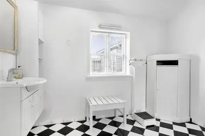 a white bathroom with a black and white checkered floor at BL395-Blokhus-Maren-Hjortelsvej-4 in Blokhus