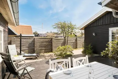 a patio with a white table and chairs and a fence at BL395-Blokhus-Maren-Hjortelsvej-4 in Blokhus