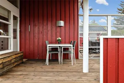 a table and chairs on a patio with a red wall at BL330-Blokhus-Lyngvej-2 in Blokhus