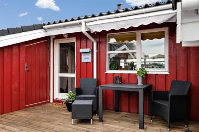 a red building with chairs and a table on a deck at BL330-Blokhus-Lyngvej-2 in Blokhus