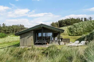 a small cabin with chairs and a porch in a field at BL1308-Saltum-Kordalsvej-124 in Saltum