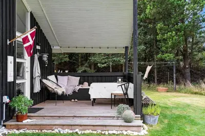 a porch with a table and a hammock on a house at BL1338-Pandrup-Lunekrogen-10 in Pandrup