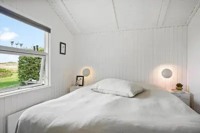 a white bedroom with a bed and a window at BL1338-Pandrup-Lunekrogen-10 in Pandrup