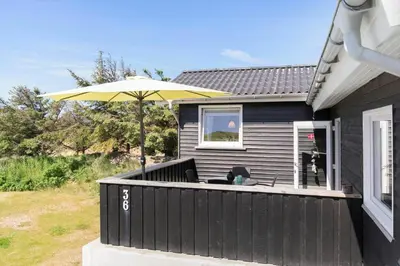 a black house with a patio with an umbrella at BL1729-Blokhus-Jens-Baerentsvej-36 in Blokhus