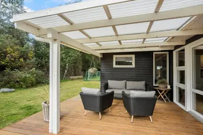 a pergola on a deck with chairs and a couch at BL1774-Blokhus-Ronliensvej-11 in Blokhus