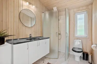 a bathroom with a sink and a toilet and a mirror at BL1774-Blokhus-Ronliensvej-11 in Blokhus