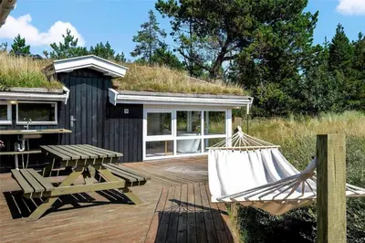 a patio with a hammock and a building with a grass roof at BL199-Saltum-Daadyrvej-22 in Saltum