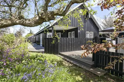 a black house with a black fence and flowers at BL475-Blokhus-Peder-Madsensvej-21 in Blokhus