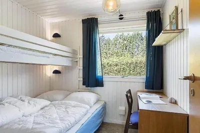 a bedroom with a bed and a desk and a window at BL1366-Blokhus-Berberisvej-56 in Blokhus