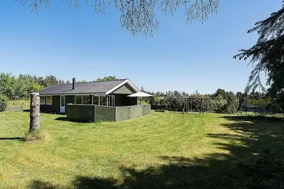 a house in a grassy field with a tree at BL1366-Blokhus-Berberisvej-56 in Blokhus