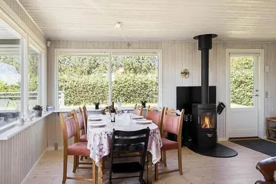 a dining room with a table and a fireplace at BL1366-Blokhus-Berberisvej-56 in Blokhus